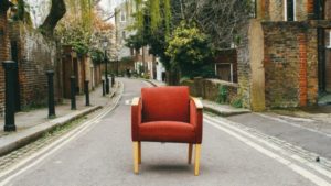 a red armchair sitting in the middle of a street