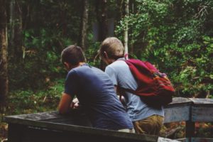 teenage boys leaning on rail wearing red backpack
